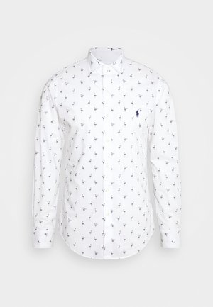 Hvid, langærmet skjorte med knapper, dekoreret med små sorte flamingo-mønstre og et mørkeblåt broderet polo-spillerlogo på brystet.