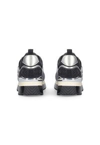 Zwarte en zilveren sport schoenen met gestructureerde zolen en trekbandjes, van achteren weergegeven tegen een witte achtergrond.