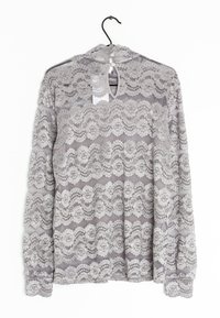 Lace langærmet top i lys grå med blomsterprint og scallopkanter. Har en knaplukning på ryggen og en nøglehuludskæring.