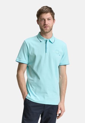 Lyseblå polo shirt lavet af bomuld, med korte ærmer, en to-knaps lukning og kontrastkanter på kraven og ærmerne.