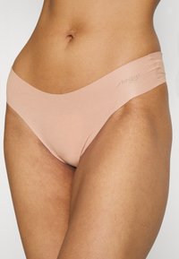 Mutande Sloggi rosa chiaro con una texture liscia e un design minimalista, dotate di una vita a bassa altezza e senza cuciture visibili.