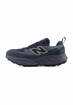 Donkerblauwe en grijze New Balance sportschoen met dikke zool en een aantreklus bij de hiel, zijaanzicht.