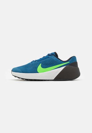 Niebieski but sportowy z jasnym zielonym logo Nike, białą środkową podeszwą oraz czarnym obcasem i spodem, widoczny z boku na białym tle.