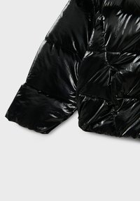 Giacca a piumino nera e lucida con sezioni trapuntate e polsino largo. Il materiale appare lucido e testurizzato, offrendo una vestibilità aderente.