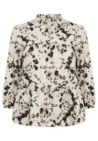 Long-sleeve blouse in cream with black and brown abstract spots. Features a ruffled neckline and a gathered hem for a relaxed fit.