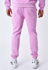 Roze katoenen sweatpants met elastische boorden, met een achterzak en een logo-detail. Gekocht met witte sneakers met zwarte accenten.