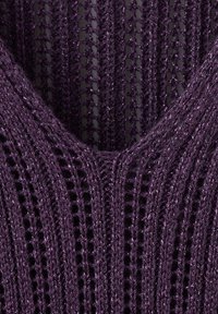 Gros plan d’un tissu tricoté violet foncé avec un motif côtelé vertical et un point ajouré.