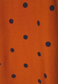 Oranssi kangas pehmeällä tekstuurilla, jossa on tasaisesti sijoitettuja tummansinisiä pallokuvioita. Sileä pinta, sopii vaatetussuunnitteluun.