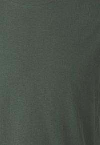 T-shirt en coton vert foncé avec un col rond. Texture lisse, sans motifs ni accents visibles. Coupe standard, design minimaliste.