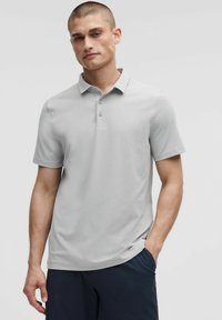 Lichtgrijze polo met een kraag, drie knopen aan de voorkant en korte mouwen, gemaakt van een gladde, stretchy stof.