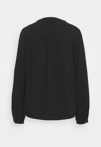 Blusa nera a maniche lunghe, con una texture di piccole punte in rilievo. Presenta un collo rotondo e polsini arricciati, con un design della parte posteriore dritta.