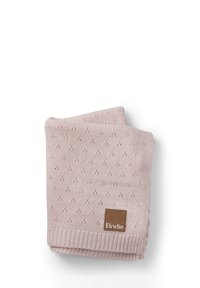 Vaaleanpunainen neulepeitto, jossa on tekstuuri pienten kohotettujen pisteiden muodossa, viimeistelty ribbineuloksella ja ruskealla logo-tarralla.