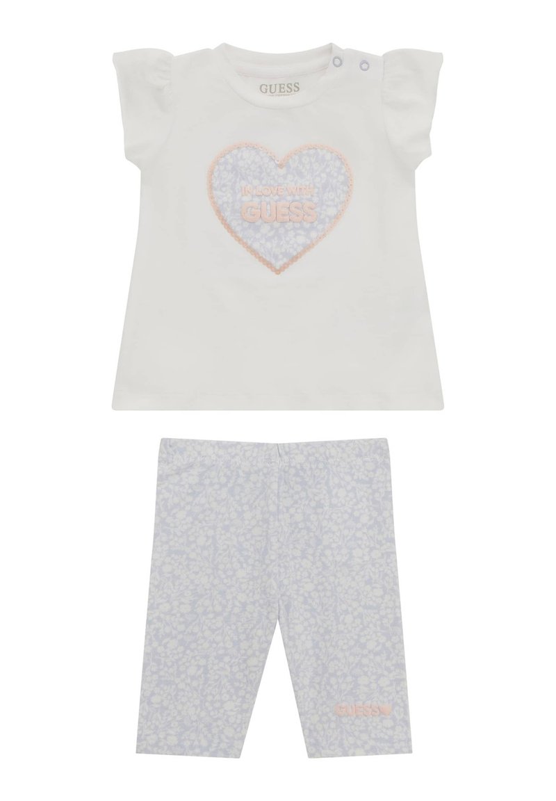T-shirt bianco in cotone con maniche corte a sbuffo, con una grafica di cuori rosa e blu; leggings abbinati con stampa floreale leggera blu.
