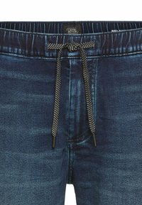 Jeans joggers i mørkeblue, med elastisk talje med snor i kontrasterende sort og hvidt mønster, samt skræddersyet ben-design.