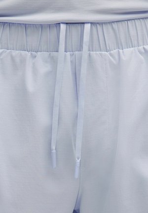 Pantalones cortos deportivos de color azul claro con una cintura elástica y dos cordones del mismo color colgando por el centro del frente.