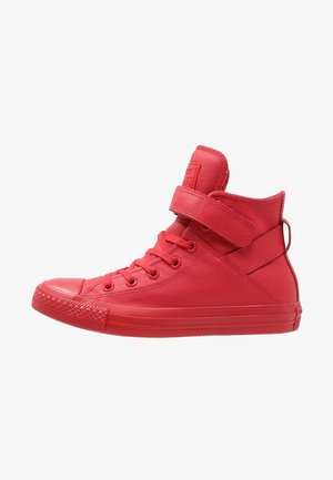 Rode hoge sneaker met veters aan de voorkant, een klittenbandsluiting rond de enkel en een gestructureerde rubberen zool en neuskap.