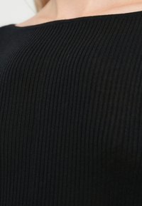 Black ribbed knit top with a wide neckline, featuring a textured fabric pattern and smooth edges, highlighting a fitted silhouette.