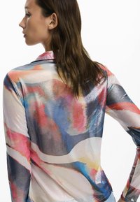 Multicolored, lightweight, long-sleeve top with a smooth, shiny finish; features abstract patterns in pink, blue, and gray tones.