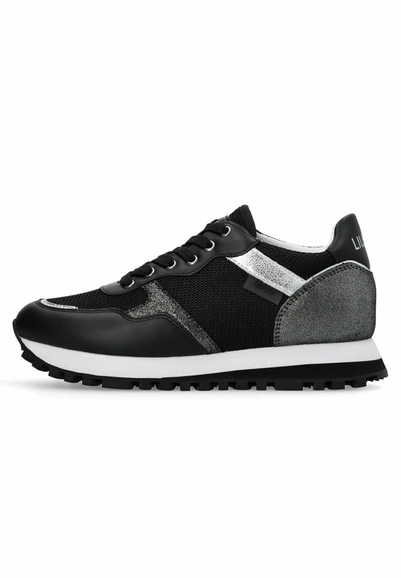 Chaussure de sport noire en mesh et cuir synthétique, accents argentés, lacets noirs, semelle intermédiaire blanche, et semelle extérieure noire texturée.