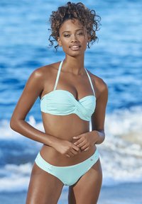 Completo bikini con strisce azzurre e bianche, caratterizzato da un top bandeau con arricciature e slip abbinati. Tessuto morbido con pochi dettagli in metallo.
