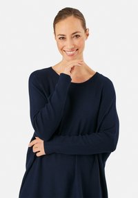 Pull en maille bleu marine à coupe décontractée avec des poignets côtelés. Il présente un décolleté large et une texture douce, conçu pour le confort.