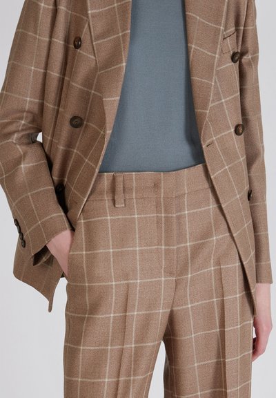 Bruin geruite blazer over een lichtblauwe gebreide top, gecombineerd met bruine geruite broeken. Bevat dubbelstaande knopen en een gladde stoftextuur.