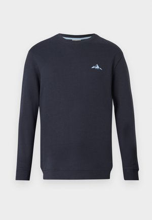 Navy modra majica s dolgimi rokavi, okroglo izrezana in z rebrastimi manšetami. Ima majhen svetlo modri logotip gore na prsih. Narejena je iz nežne tkanine.