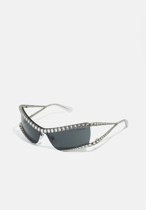 Mustika pruunidega elegantsed prillid mustas raamistikus, tumedate läätsedega ja hõbedaste aksessuaaridega. Ülalt ja külgedelt kulgeb rida selgeid kristalle.