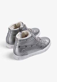 Zapatillas de deporte altas de cuero metálico plateado. Presenta un diseño de calavera, paneles laterales texturizados y un cierre con cremallera para facilitar el uso.