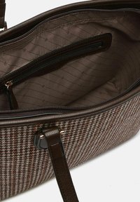 Brązowa torebka w kratę z gładkimi skórzanymi wykończeniami. Wnętrze ma pikowaną brązową podszewkę oraz liczne kieszenie z zamkami błyskawicznymi.