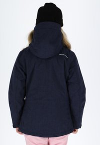 Granatowa wodoodporna kurtka z wysokim kołnierzem, regulowanym kapturem i logo na plecach. Gładka tekstura z delikatnym melanżowym wzorem.