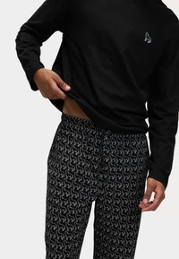 Svart långärmad skjorta med en liten broderad design. Svarta byxor med ett upprepat vitt djurmönster, elastisk midja och dragsko.