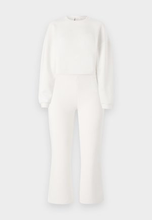 White sweatshirt with long sleeves and a crew neckline, paired with high-waisted, flared sweatpants in matching white fabric.