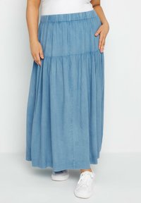 Ljusblå, lager-på-lager maxi kjol med elastisk midja och sidofickor. Tillverkad av mjukt tyg, kombinerad med vita sneakers.