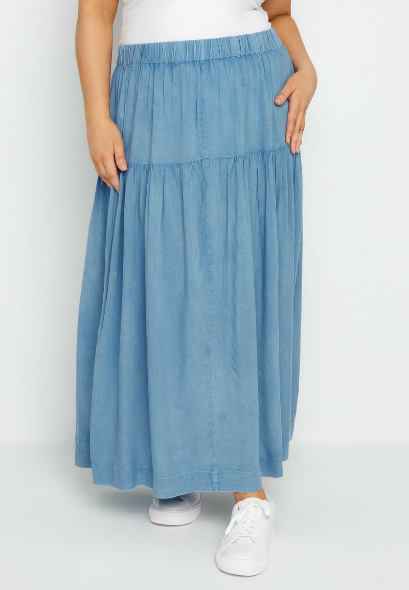 Ljusblå, lager-på-lager maxi kjol med elastisk midja och sidofickor. Tillverkad av mjukt tyg, kombinerad med vita sneakers.