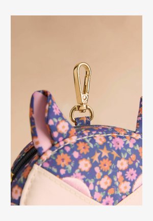 Virágmintás anyag lila, rózsaszín és narancssárga virágokkal, két hegyes füllel és aranyszínű fém csattal a tetején.