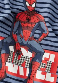 Materiał w niebieskie i granatowe paski z grafiką czerwono-niebieskiego superbohatera, z czarnymi akcentami i wyrazistym tekstem poniżej.