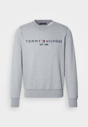 Harmaa huppari, joka on valmistettu pehmeästä kankaasta. Siinä on pyöreä pääntie, pitkät hihat ja "TOMMY HILFIGER EST. 1985" -logo tummansinisellä rinnassa.