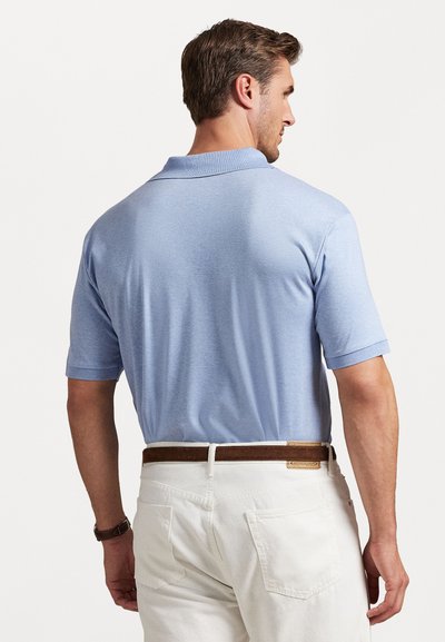 Ανοιχτό μπλε πόλο μπλουζάκι με κοντά μανίκια, με κλασικό γιακά και λεία υφή, συνδυασμένο με λευκούς παντελόνες και καφέ δερμάτινη ζώνη.