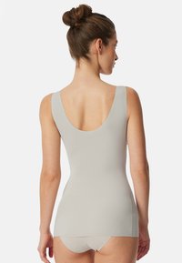 Bodysuit gris clair avec un dos dégagé, fabriqué dans un tissu lisse et extensible, avec un design ajusté, associé à une culotte assortie.