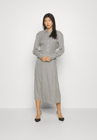 Black and white patterned midi dress with a button-up design, long sleeves, and a smooth fabric, featuring a scallop-like print.