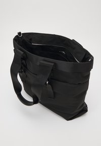 Borsa a tracolla nera realizzata in tessuto resistente, con doppio manico superiore, molteplici tasche esterne e un compartimento interno con zip.