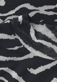 Schwarzes und weißes, zebra gestreiftes Gewebe mit einem strukturierten Netzmuster, das dynamische, gewundene Linien und sanfte Kanten zeigt.