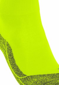 Neon-gelbe Sportsocke mit einem strukturierten Design, versehen mit einem gerippten Bund und einem dunkleren Akzentmuster an der Seite.