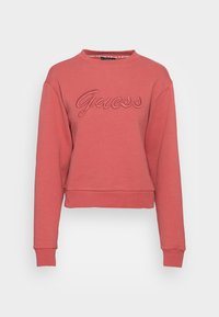 Korálově růžová mikina s kulatým výstřihem a dlouhými rukávy, s vyšitým vyvýšeným logem "Guess" umístěným na hrudi.