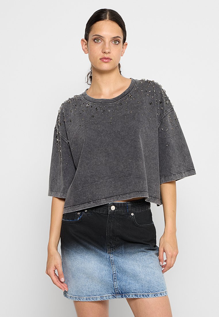 Grau gekürzter Sweatshirt mit Perlenakzenten an den Schultern, kombiniert mit einem schwarzen und blauen Verlauf-Jeansrock.