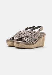 Sandalias de cuña con parte superior metálica trenzada, correa ajustable en el tobillo y suela de plataforma envuelta en yute en un color metálico claro.