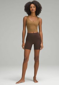 Pruun lühem top, millele on sobitatud kõrge vöökoht, tumepruunid lühikesed püksid, mõlemad valmistatud venivast kangast. Sile tekstuur ja keha lähe disain.