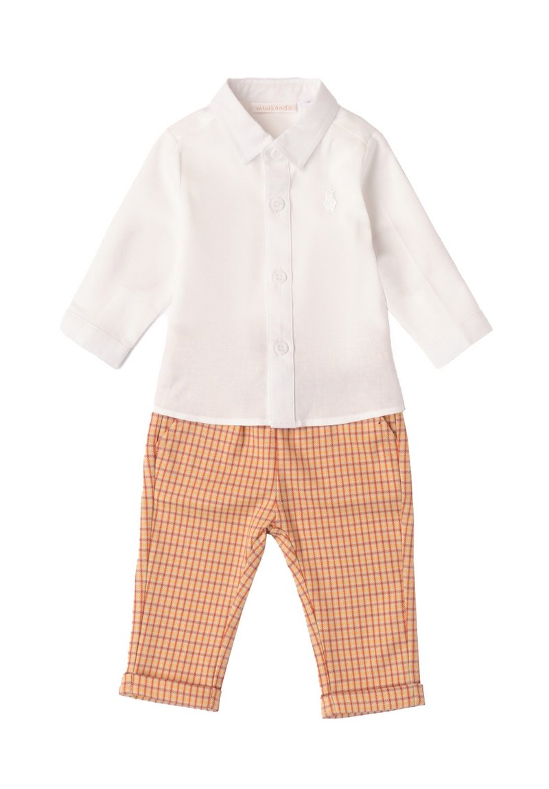 Camisa blanca de manga larga con cierre de botones y un pequeño logo, combinada con pantalones a cuadros naranjas con puños doblados y bolsillos.