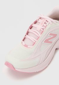 Nærbilde av en rosa og hvit New Balance-sneaker med mesh-overdel, rosa skolisser og merkets "N"-logo på siden.